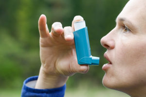 Asthma patient inhaling medication for treating shortness of breath and wheezing. Chronic disease control allergy induced asthma remedy and chronic pulmonary disease concept.