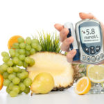 Diabetes concept glucose meter in hand and healthy organic food lemon water pear grapes fresh orange isolated on a white background