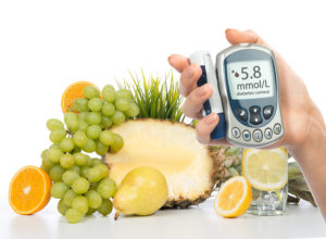 Diabetes concept glucose meter in hand and healthy organic food lemon water pear grapes fresh orange isolated on a white background