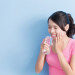 woman drink water with sensitive teeth isolated on blue background