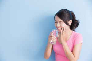 woman drink water with sensitive teeth isolated on blue background